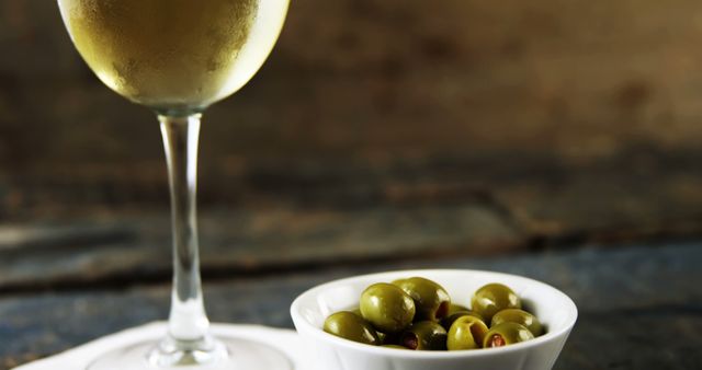 Chilled White Wine Glass and Bowl of Green Olives in Cozy Ambiance - Download Free Stock Images Pikwizard.com