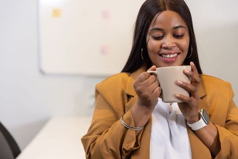 African american professional woman enjoying coffee during meeting in modern office