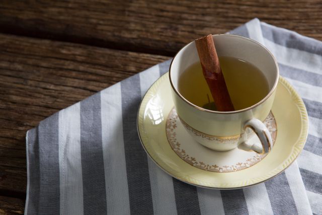 Close-up of tea cup with cinnamon stick on napkin