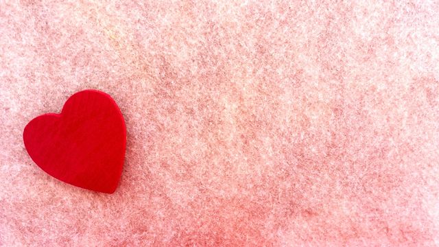 Close up view of a red heart against pink textured background. Love and valentine's day concept