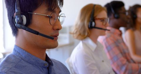 Diverse customer service team using headsets in office environment