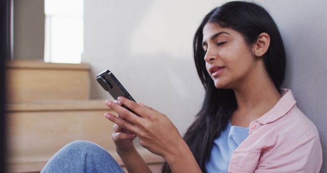 Image of happy biracial woman sitting on stairs and using smartphone - Download Free Stock Photos Pikwizard.com