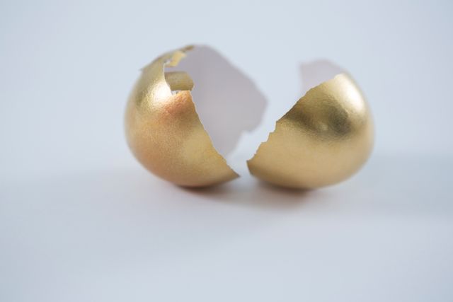 Close-up of broken golden Easter egg on white background