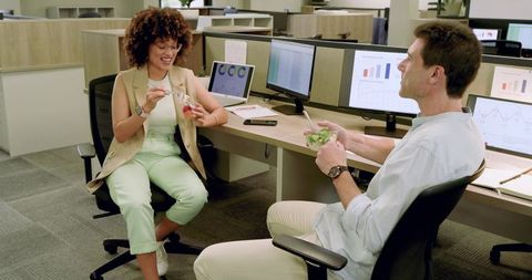 Coworkers enjoying casual chat with healthy lunch in modern office