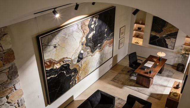 Large abstract marble artwork illuminating luxury office with warm track and desk lighting