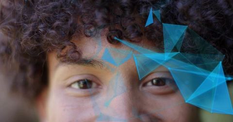 Gazing young man with curly hair wearing futuristic blue polygonal holographic overlay