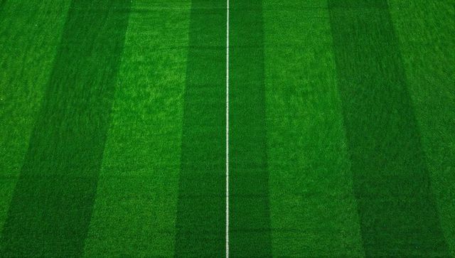 Top-down striped soccer pitch with center line dividing vibrant green turf symmetry