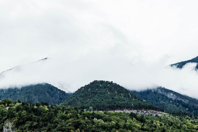 Misty clouds are descending upon forest-covered mountains, creating a serene and tranquil scene. Ideal for uses in travel promotions, nature-themed posters, environmental blogs, or scenic backgrounds for presentations. Perfect for conveying peace, tranquility, and the beauty of nature.