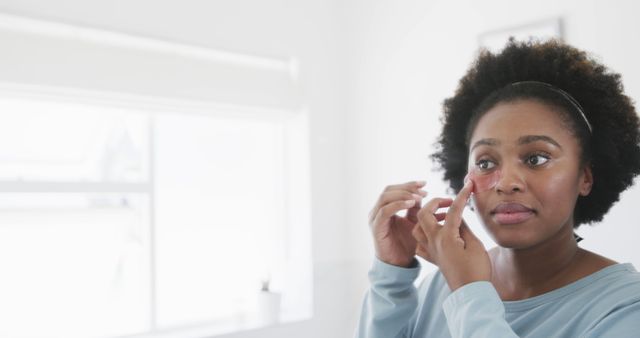 Woman Applying Skincare Product to Face in Bright Bathroom - Download Free Stock Images Pikwizard.com