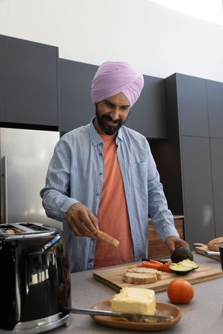 Man in purple turban prepares toast in minimalist kitchen