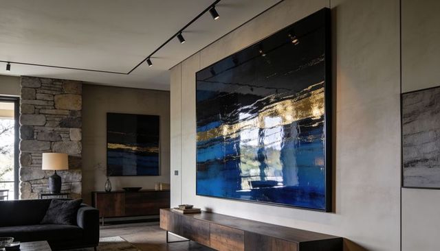 Oversized glossy blue gold abstract artwork in modern living room with stone column