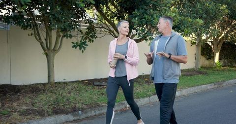 Middle Aged Couple Walking with Coffee Cups Outdoors