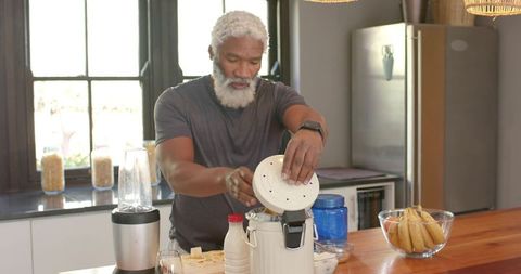 Mature man preparing healthy smoothie in modern kitchen