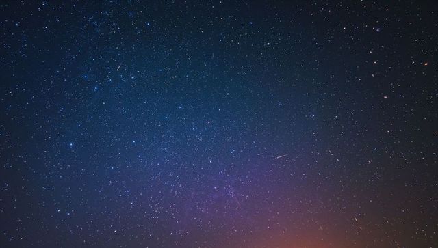 Serene night sky with shooting star and subtle purple glow