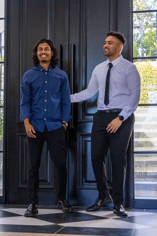 Smiling indian colleagues standing in foyer wearing dress shirts and watches, corporate teamwork