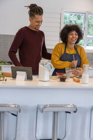 African american couple cooking together at modern kitchen island woman stirring bowl