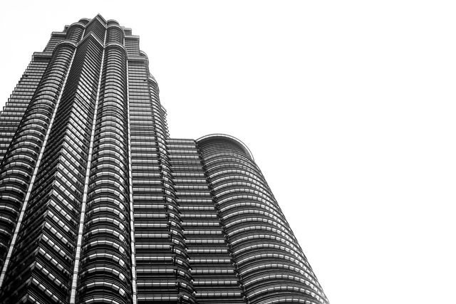 Modern urban skyscraper with intricate architectural design captured in black and white. Ideal for use in business materials, articles about architecture, urban development, financial districts, and contemporary design themes.