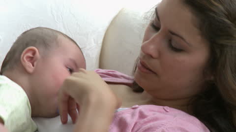 Mother Relaxing on Sofa with Baby at Home