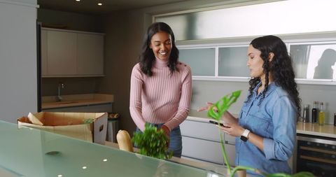 Diverse female friends enjoy grocery unpacking in modern kitchen