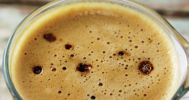 Perfect for use in coffee shop menus, websites, blogs about coffee, or promotional materials for coffee brands. This image highlights the rich texture and frothy crema of a freshly brewed espresso, making it appealing for any content aiming to evoke a sense of warmth and satisfaction.