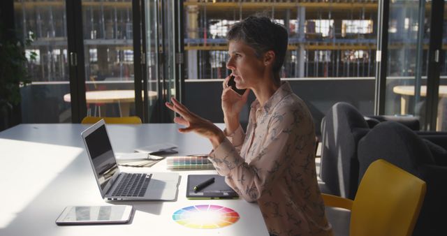 Businesswoman Discussing Projects on Phone in Modern Office with Laptop - Download Free Stock Images Pikwizard.com