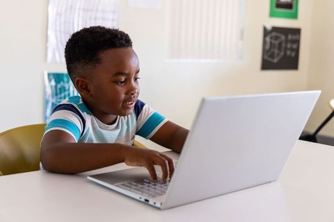 African American Boy Learning on Laptop in Bright Classroom, Remote Learning Technology