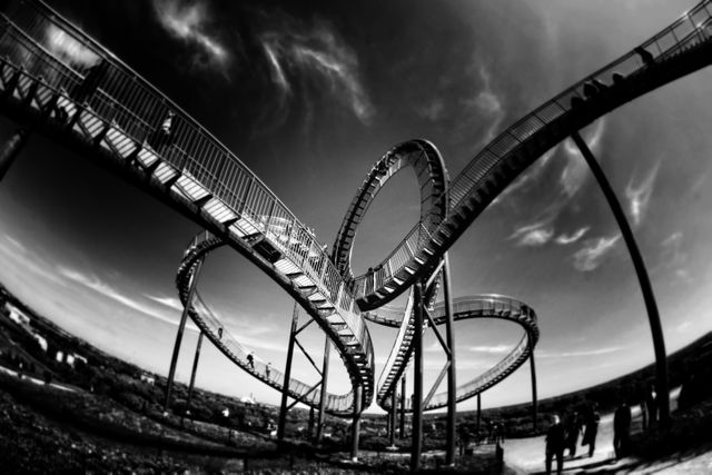 Displaying a roller coaster with dramatic looping tracks captured in a black and white abstract style. Ideal for use in industrial design presentations, amusement park promotions, or artistic photography collections. Creates a sense of thrill and excitement, suitable for projects seeking to convey drama, adventure, or innovative architecture.