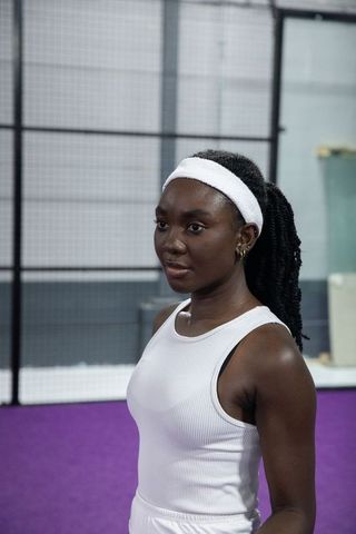 African american woman standing on purple court wearing white headband and ribbed tank