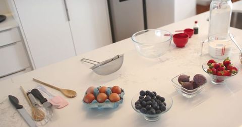 Bright modern kitchen island displaying baking ingredients and utensils for fruit tarts