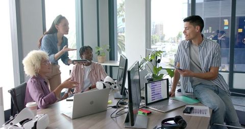 Diverse team collaborating with laptops and vr in modern office