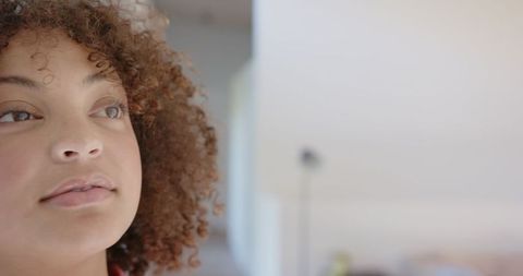 Curly-Haired Woman Looking Upward in Bright Living Room