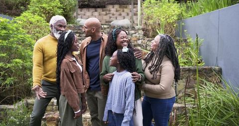 Multigenerational Black Family Laughing and Embracing on Terraced Garden Steps Outdoors