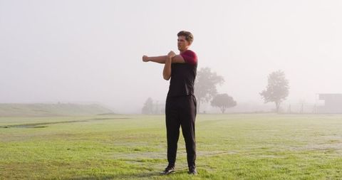 Athlete stretching on green field at dawn
