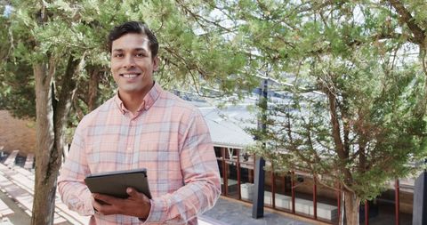 Smiling male teacher with tablet in outdoor school environment