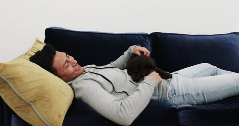 Relaxed Asian Man Lounging with Puppy on Stylish Couch at Home