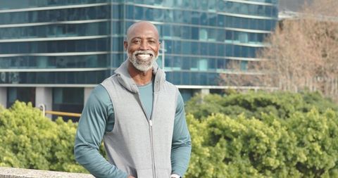 Senior African American man standing on urban terrace smiling while checking smartwatch