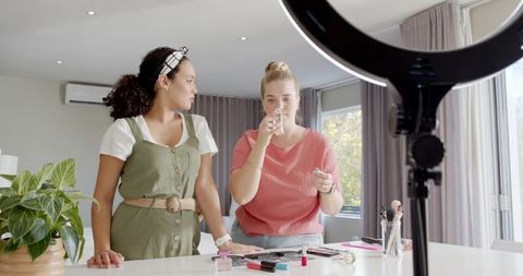 Diverse female friends filming makeup tutorial with ring light