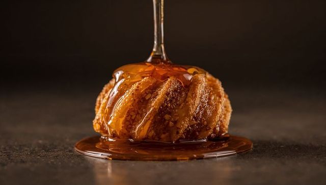 Amber Caramel Drizzling Over Nut-Crusted Swirl Pastry, Glazed Brioche Bundt on Dark Matte Surface