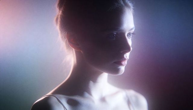 Cinematic young woman posing in moody backlit portrait with rim light and soft haze