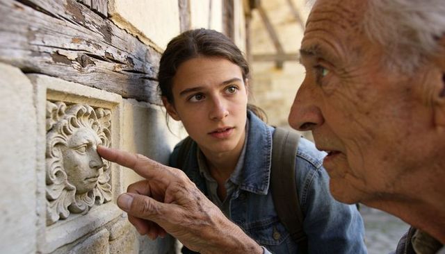 Elder guide pointing at carved sun medallion, young explorer watching in courtyard