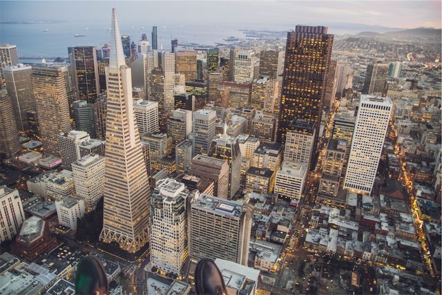 Showing a breathtaking aerial view of San Francisco cityscape during sunset. The image highlights the iconic skyscrapers, modern and historic buildings, and urban layout with a tranquil ocean in the background. Ideal for urban development projects, travel magazines, architecture portfolios, and city-themed advertising.