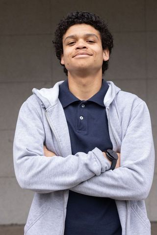 Confident african american young man standing arms crossed in gray hoodie urban portrait