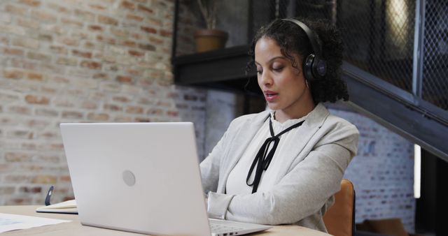 Focused businesswoman using laptop and headset - Download Free Stock Images Pikwizard.com