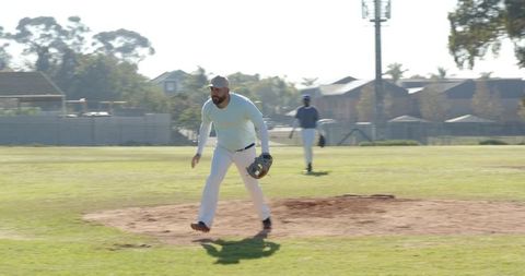 Male Teammate Stepping Off Pitcher's Mound During Community Baseball Practice in Sunlight