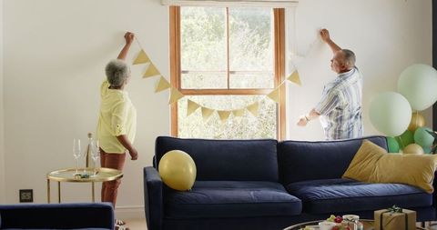 Senior couple decorating living room for celebration with bunting