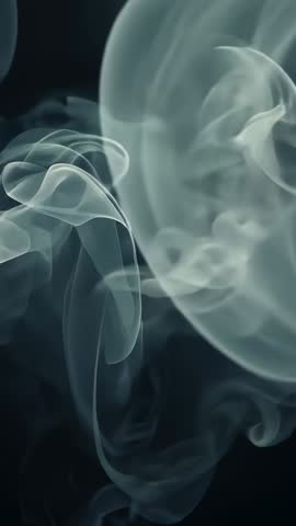 Vertical vapor wisps and smoke rings curling in dark studio — cinematic fogger test video