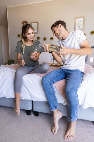 Young Couple Relaxing on Bed with Champagne Flutes