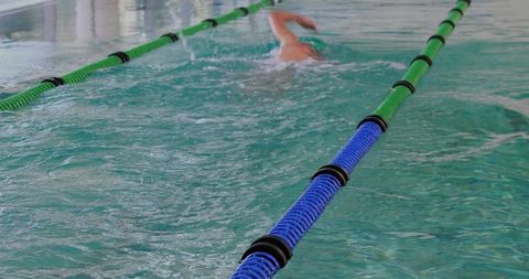 Competitive swimmer swimming freestyle along blue and green lane dividers in pool