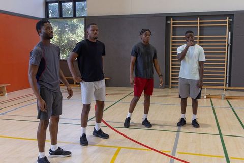 African american men standing on gym court preparing for basketball training session