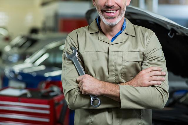 Mid-section of mechanic with arms crossed in repair garage